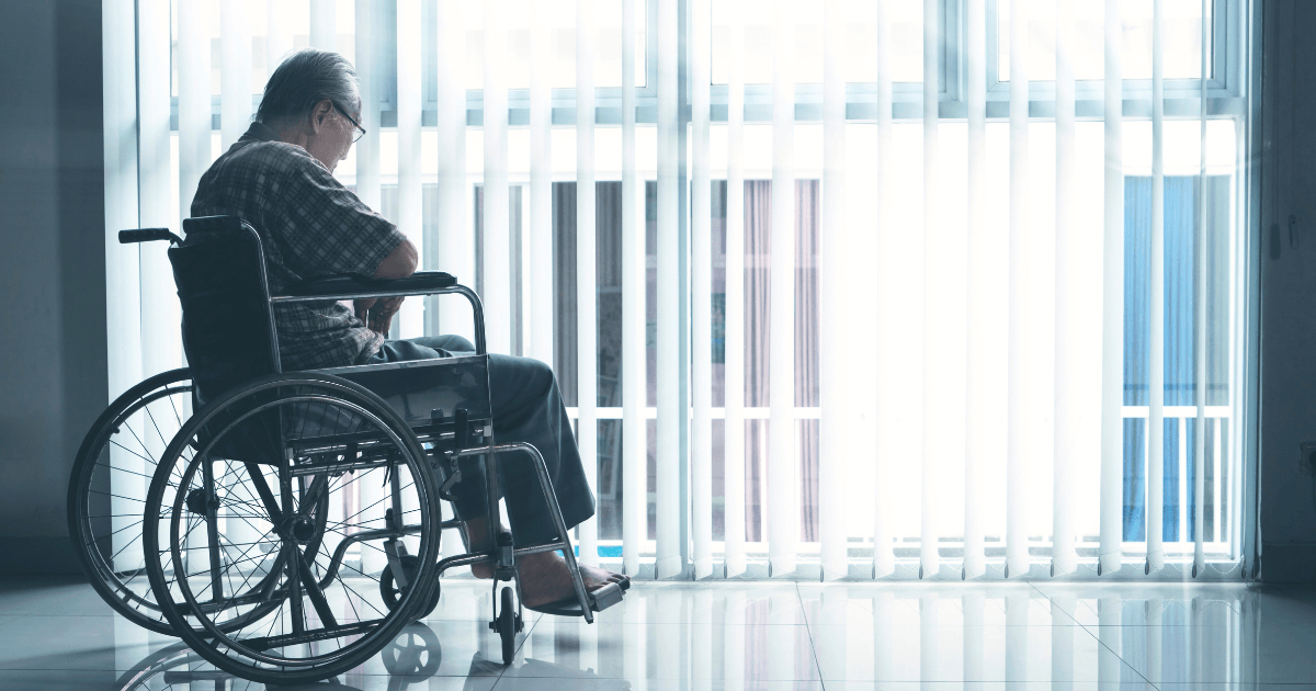 窓辺で車椅子に座り、静かに外を眺める高齢者の後ろ姿