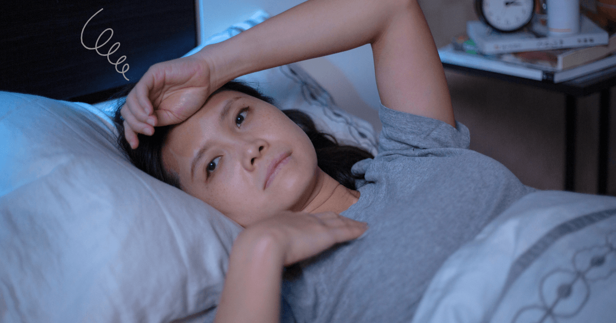 夜、ベッドで眠れずに目が冴えている女性。頭上にぐるぐるマークがあり、睡眠の悩みを表している。